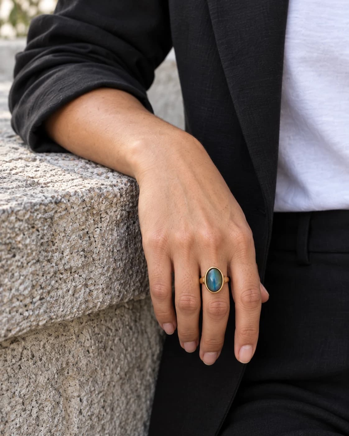 Editorial hand detail with an oval ring on a weathered stone ledge — AI styling preview